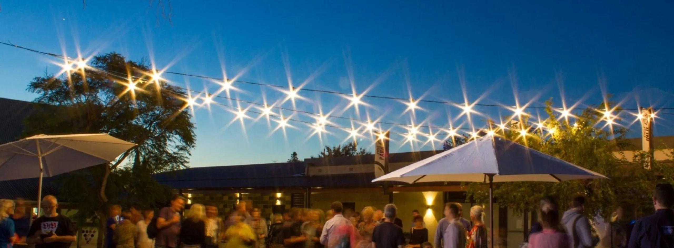 Twilight shot of the Barossa Makers & Beyond Market with crowds, umbrellas and stall holders