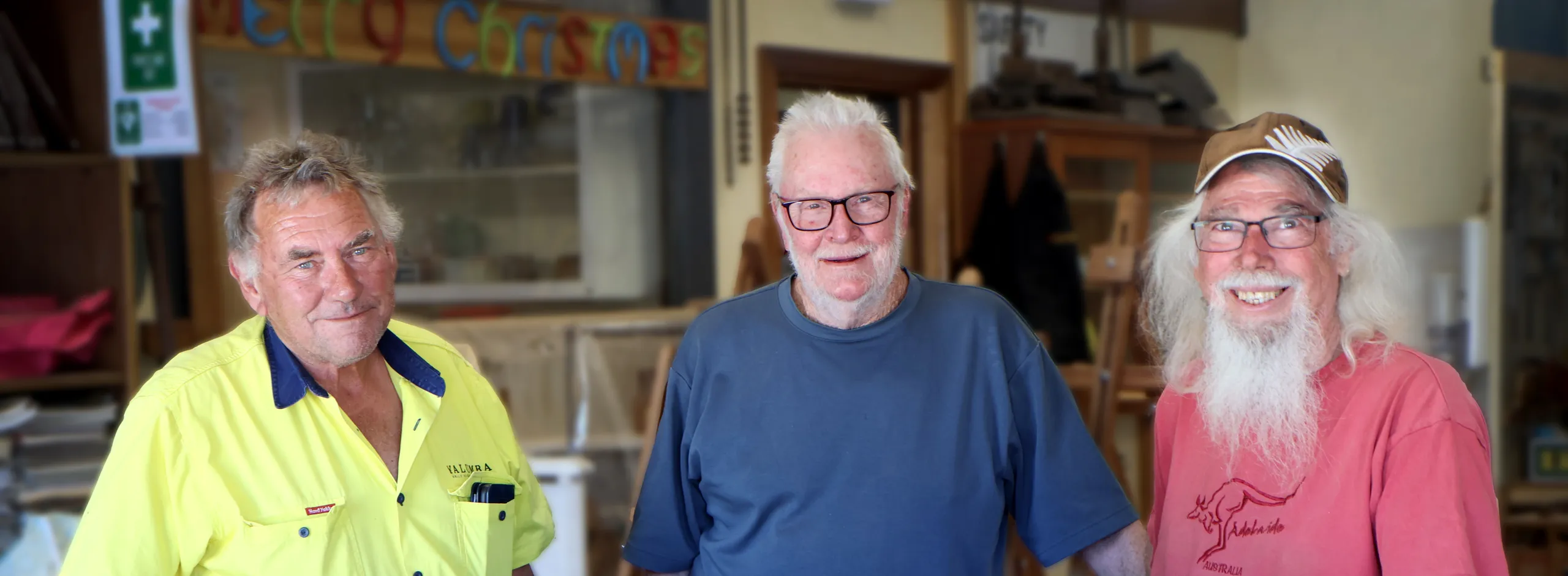 Three men with wooden toys made at the Community Men's Shed