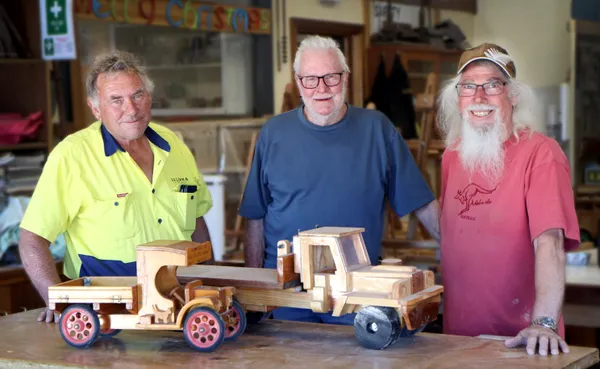 Three men with wooden toys made at the Community Men's Shed
