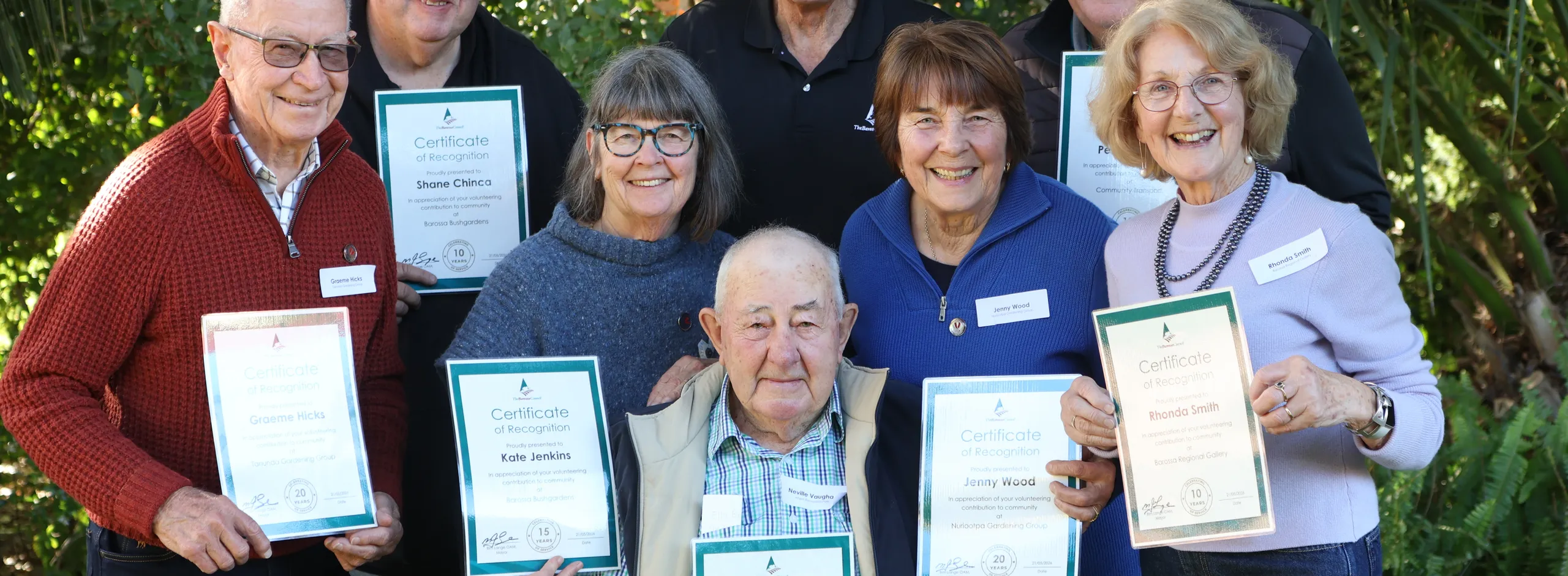 group of volunteers holding certificates of appreciation presented to them by Mayor Lange who is in the centre of the photo