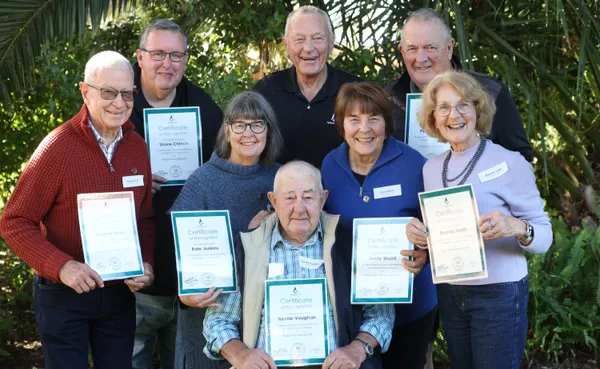 group of volunteers holding certificates of appreciation presented to them by Mayor Lange who is in the centre of the photo