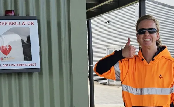 Young council worker giving the thumbs up after installing a defibrillator at another Council building