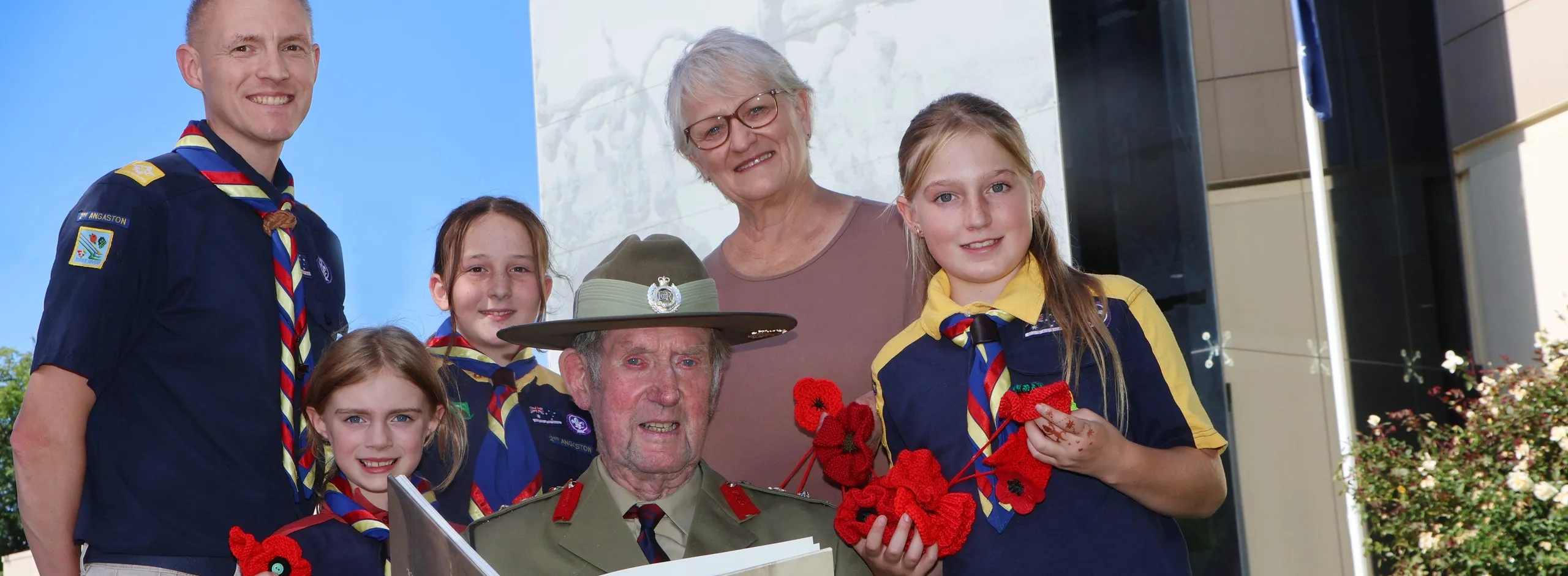 Three young scouts, their scout leader, and RSL member wearing uniform and medals and a local historian standing in front of the Barossa Council office