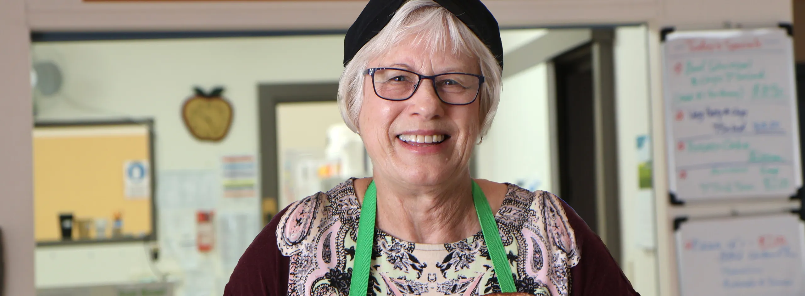Volunteer cafe assistant holding a cup and plate of scones