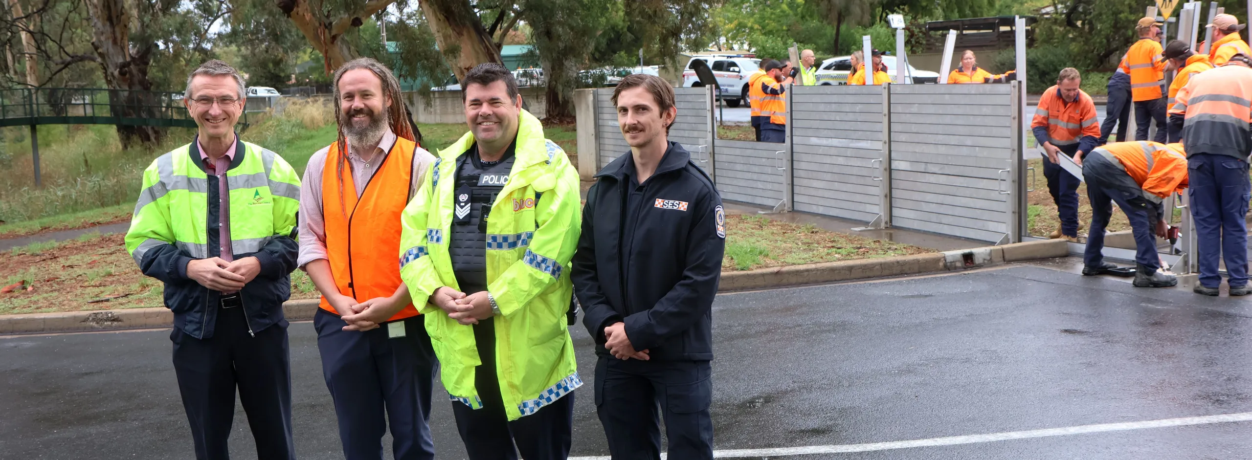 Flood wall drill showing SES and Police officer with Council staff installing wall in background