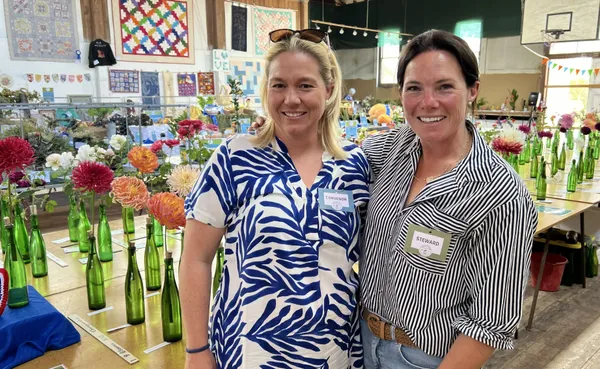 Two women standing in front of a table filled with Dahlias ready for adjudication