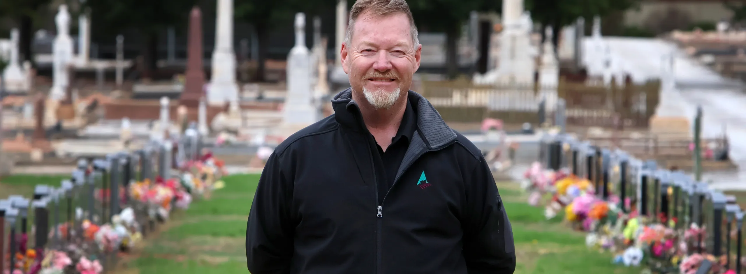 Jack Denherder standing on the lawns at Nuriootpa Cemetery with historic headstones in the background