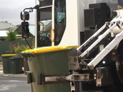 Yellow kerbside bin tipped into recycling truck