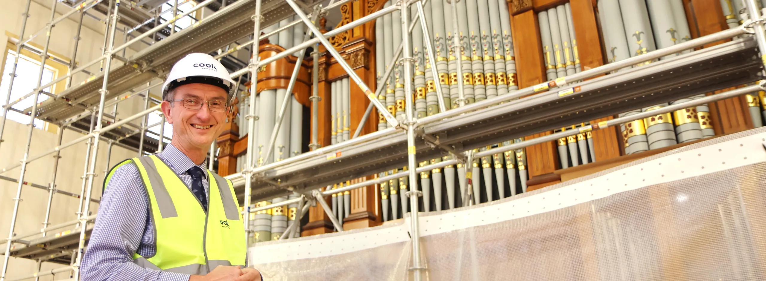 Steven Kaesler in front of the partially wrapped 1877 Hill&Song Grand Organ