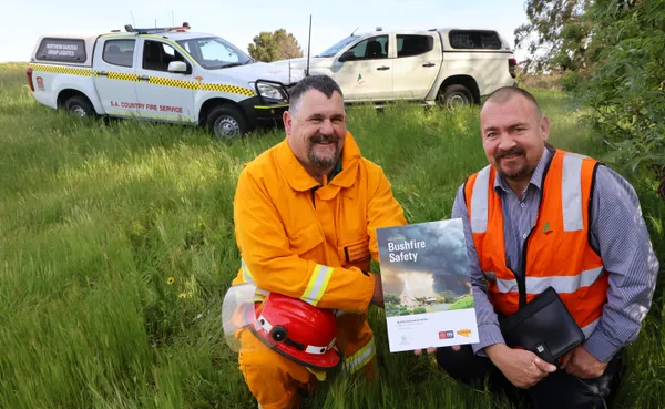 CFS and Council officer with bushfire safety information shown inn high grass in the lead up to fire danger season