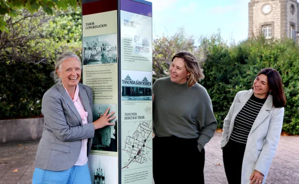 Three women with a heritage sign in the heart of Tanunda