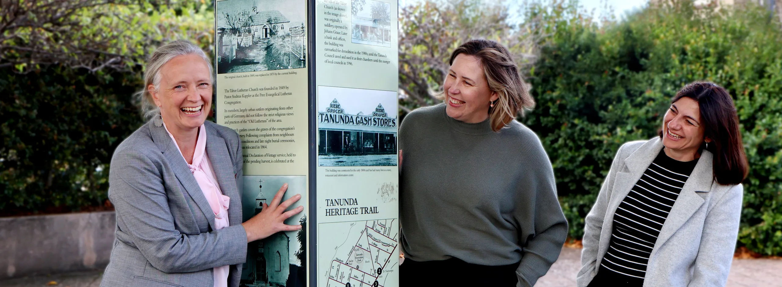 Three women with a heritage sign in the heart of Tanunda