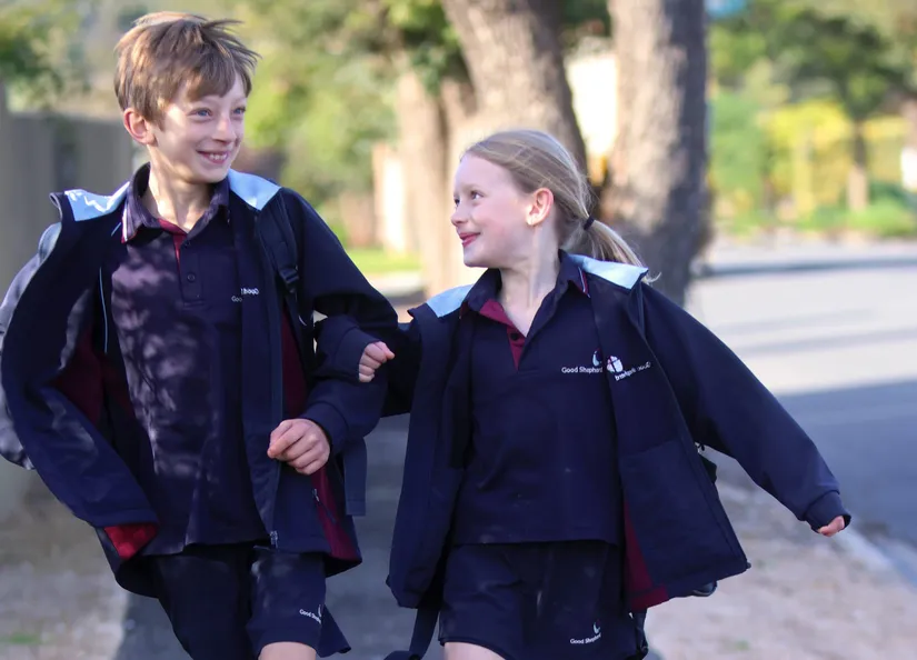 two children skipping along a recently sealed footpath on their way to school