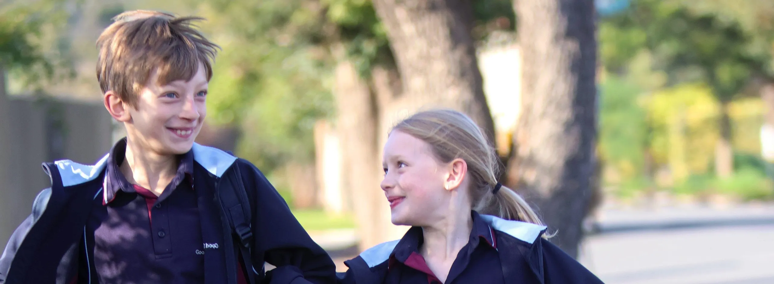 two children skipping along a recently sealed footpath on their way to school
